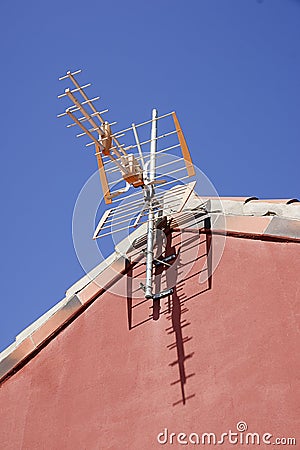 Vertical shot of an antenna attached to a red house on a clear blue background Stock Photo