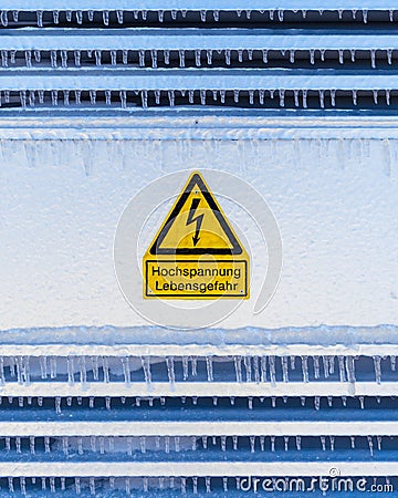 Vertical shot of Attention! High voltage sign in German on frozen surface Stock Photo