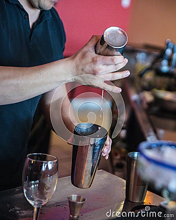 Vertical shot of a bartender in black mixing a cocktail in metal cups Stock Photo