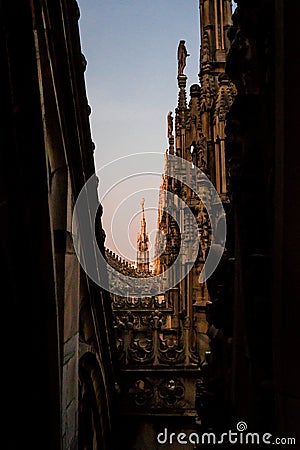 Vertical shot of a beautiful view of Duomo di Milano from a dark narrow alley in Milan, Italy Stock Photo