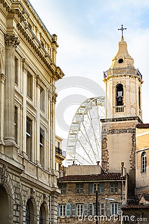 Vertical shot of The bell tower of Saint Ferreol and observation wheel in Marseille France Stock Photo