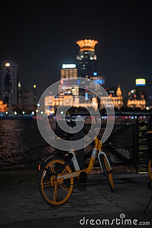 Vertical shot of a bicycle on a street with city view of Shanghai in China at night Editorial Stock Photo