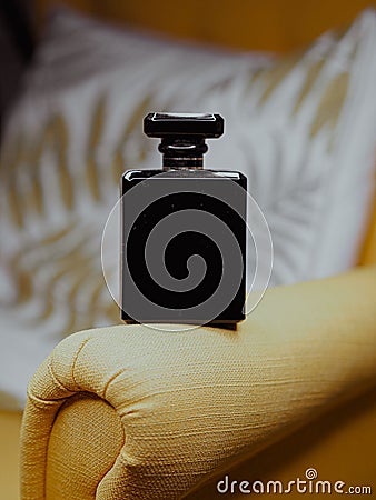 Vertical shot of a black aesthetic perfume bottle on yellow furniture Stock Photo