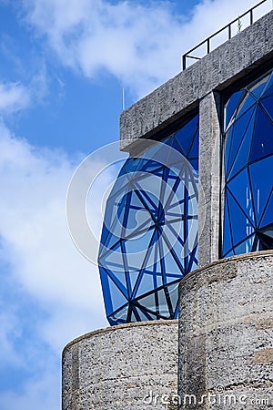 Vertical shot of blue glass paned window bulging out from concrete frames - artistic architecture Stock Photo