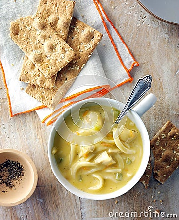 Vertical shot of a bowl of creamy turkey noodle soup served with crispbread with sesame Stock Photo