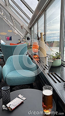 Vertical shot of a cafe table with a glass of beer and blue armchairs Editorial Stock Photo