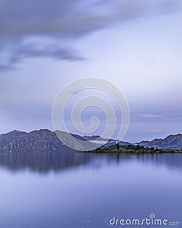 Vertical shot of a calm reflective lake on a mountain range background Stock Photo