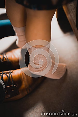 Vertical shot of a child standing on her father's feet in order to learn to walk Stock Photo