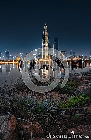 Vertical shot of the China Huarun Building at night with a view of a pier and cityscape with lights Editorial Stock Photo