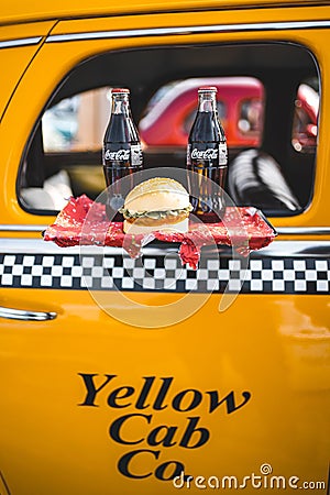 Vertical shot of a classic American yellow cab taxi with coca cola bottles and a hamburger Editorial Stock Photo