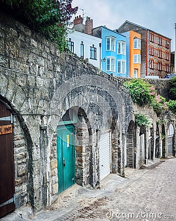 Vertical shot of cobblestone alley colorful buildings in background Penniless Cove hill Tenby Wales Stock Photo