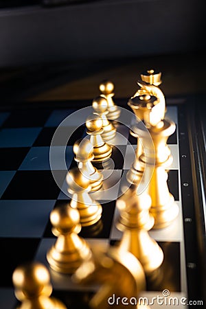 Vertical shot of cool gold chess pieces in the starting position reflected on the board Stock Photo