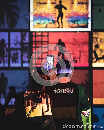 Vertical shot of a couple taking photos of light art installations in Singapore Editorial Stock Photo