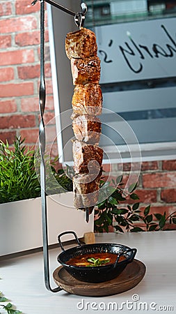 Vertical shot of delicious barbeque hanging over a bowl of soup Stock Photo