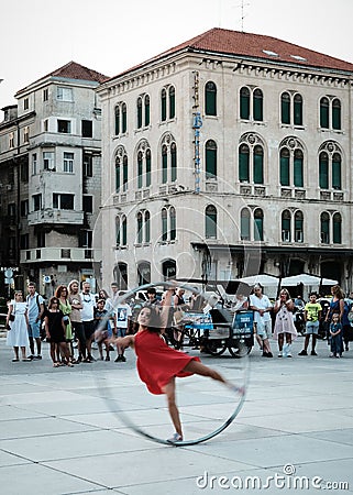 Vertical shot of a female doing an acrobatic show with a hoop at the Split Promenade, Croatia Editorial Stock Photo