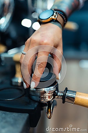 Vertical shot of a female hand suppressing and leveling the coffee powder Stock Photo