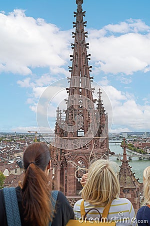 Vertical shot of females looking at the Basel Minister building during daytime in Basel, Switzerland Stock Photo