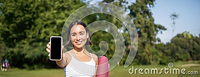 Vertical shot of fit and healthy young asian woman, shows smartphone screen with her workout stats, recommends telephone Stock Photo