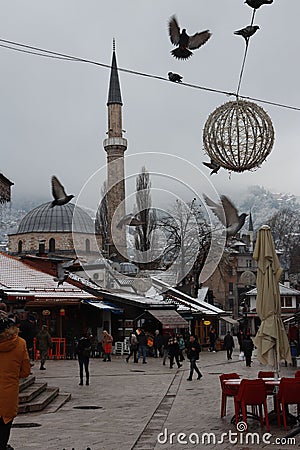 Vertical shot of a flock of pigeons taking flight from a busy market in Sarajevo Editorial Stock Photo