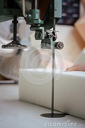 Vertical shot of a foam cutter machine, cutting through an upholstery foam Stock Photo