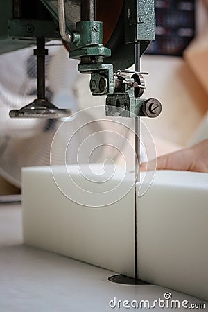 Vertical shot of a foam cutter machine, cutting through an upholstery foam Stock Photo