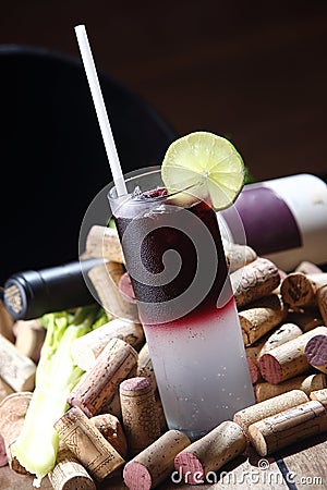 Vertical shot of a glass of a vodka cranberry cocktail drink surrounded with wine corks Stock Photo