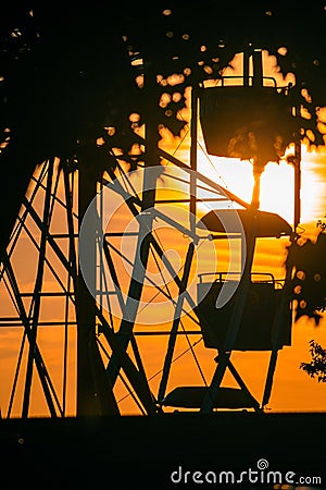 Vertical shot of the golden sunset over the silhouette of the Ferris wheel in the park Stock Photo
