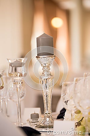 Vertical shot of gray candle on transparent silver glass candlestick on wedding reception table Stock Photo
