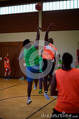 Vertical shot of a group of young people playing basketball in an indoor court in Kleve, Germany Editorial Stock Photo