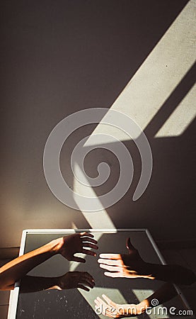 Vertical shot of the hands of two people reaching for each other under the sunlight Stock Photo