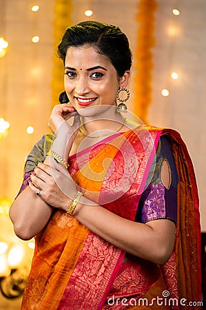 Vertical shot of happy smiling indian girl standing with in traditional ethnic wear by looking at camera at home - Stock Photo
