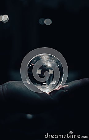 Vertical shot of a human's palm holding a shining glass ball on an isolated background Stock Photo