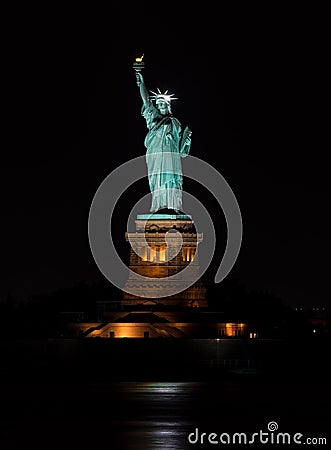 Vertical shot of the iconic Statue of Liberty and a full moon at night Stock Photo