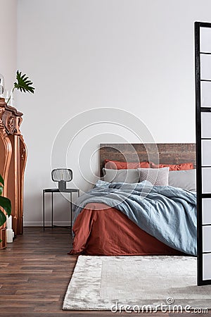 Vertical shot of industrial bedroom with hardwood floors, copper fireplace portal and wooden bed Stock Photo