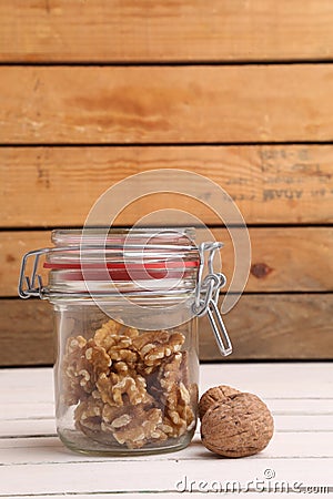 Vertical shot of a jar of walnuts under the lights on a wooden table Stock Photo