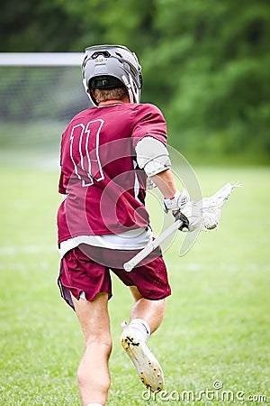 Vertical shot of a lacrosse player running in a sports field Editorial Stock Photo