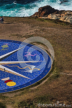 Vertical shot of a large blue compass built on the shore in front of the ocean in La Coruna, Spain Stock Photo