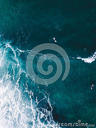 Vertical shot of lazur ocean waters with distanced boats and a corner of wavy white foam Stock Photo