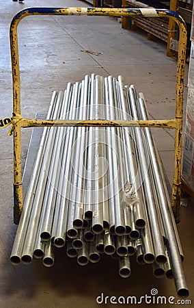 Vertical shot of long silver pipes on a yellow rolling cart in a department store Stock Photo