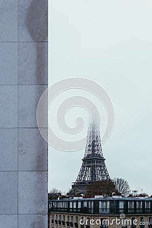 Vertical shot of the lower part of the famous Eiffel tower with the top covered with fog Stock Photo