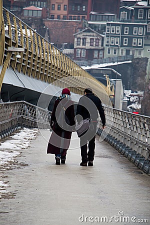 Vertical shot of a male and a female walking through the bridge on a cold winter day Editorial Stock Photo