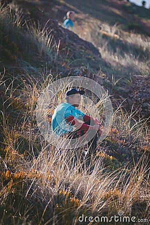 Vertical shot of a male surfer relaxing at the grassy shore of the ocean Editorial Stock Photo
