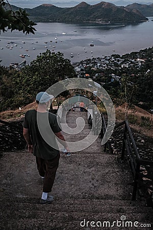 Vertical shot of a man walking down the stairs of Mount Tapyas in Coron Island, Palawan, Philippines Stock Photo