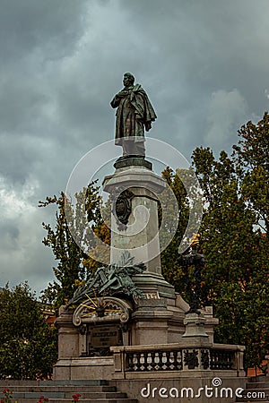 Vertical shot of Monument of Adam Mickiewicz against gray clouds Stock Photo