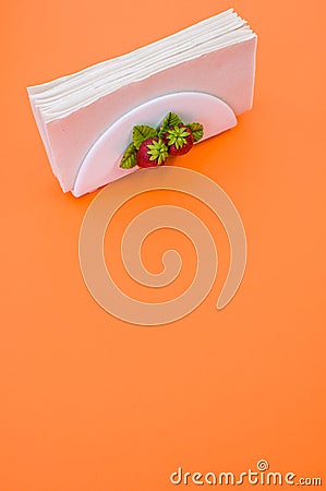 Vertical shot of a napkin holder with strawberry detail on orange background Stock Photo