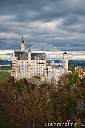 Vertical shot of the Neuschwanstein Castle surrounded by high trees in cloudy weather Editorial Stock Photo