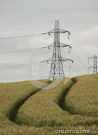 Vertical shot of overhead electric power transmission towers standing in a field Stock Photo