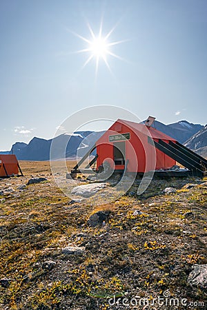 Vertical shot of Owl River emergency shelter in remote arctic wilderness with a backpack in front of it . Sunny day in Stock Photo