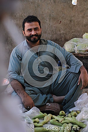 Vertical shot of a Pakistani male with a beard in a market selling fruits in a shalwar kameez Editorial Stock Photo