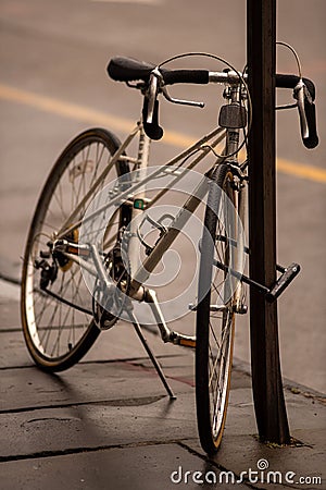 Vertical shot of a parked bicycle at the side of a road Editorial Stock Photo